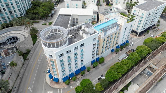 High-angle view of a multi-story building with a rooftop swimming pool and surrounding streets.