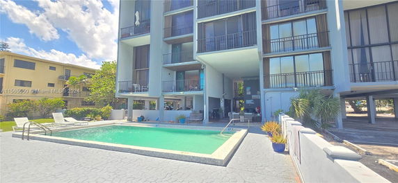 View of a residential building with a swimming pool in front.