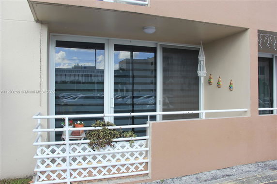 Front view of a building with a small balcony decorated with plants and wall ornaments.