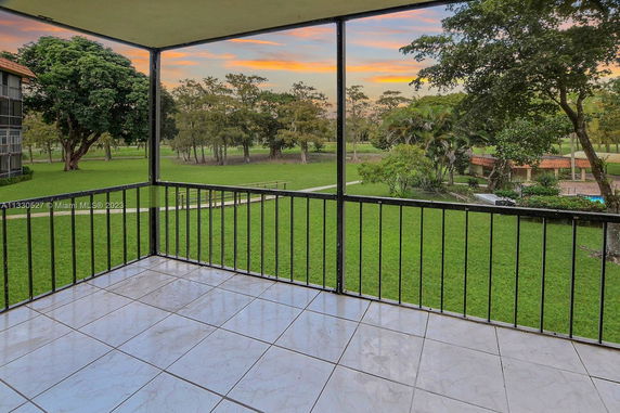 View from a balcony overlooking a grassy area with trees and distant landscape.