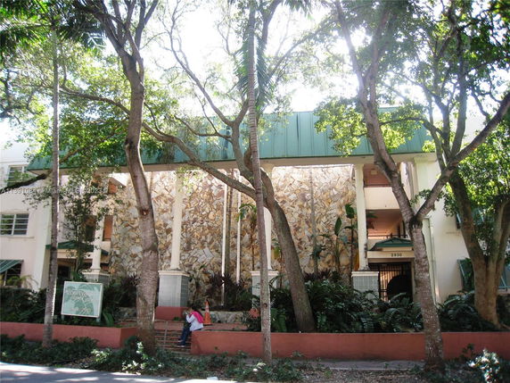 Front view of a multi-story building with stone façade and green roof.