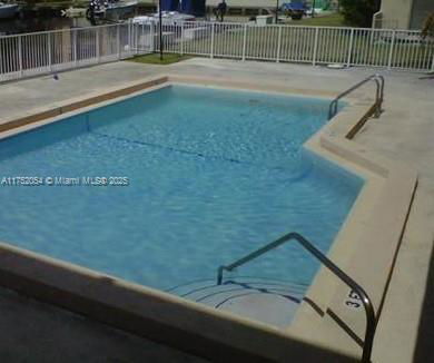 Outdoor swimming pool with safety railing and surrounding fence.