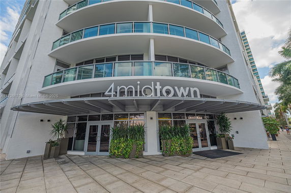 Front view of a multi-story building with curved balconies and a canopy entrance.