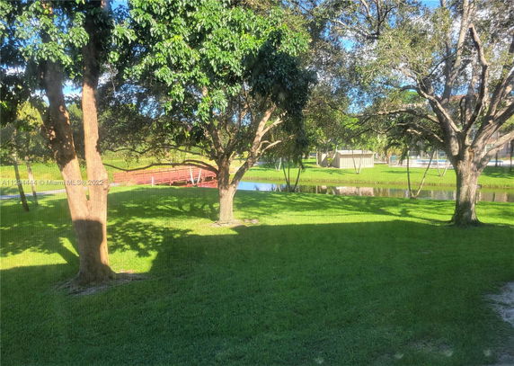 Scenic view of a grassy area with trees and a small bridge over a water body.