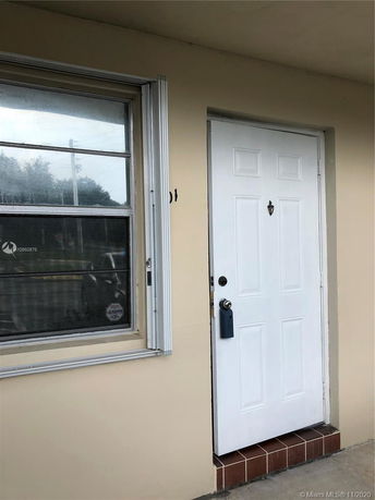 Front view of a building with a white door and a window.