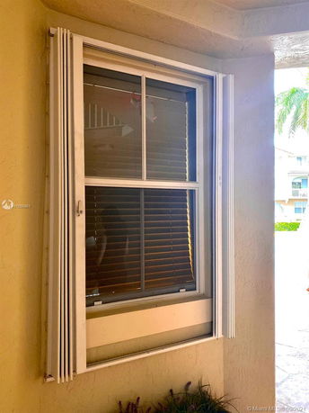 Exterior view of a window with hurricane shutters on a building wall.