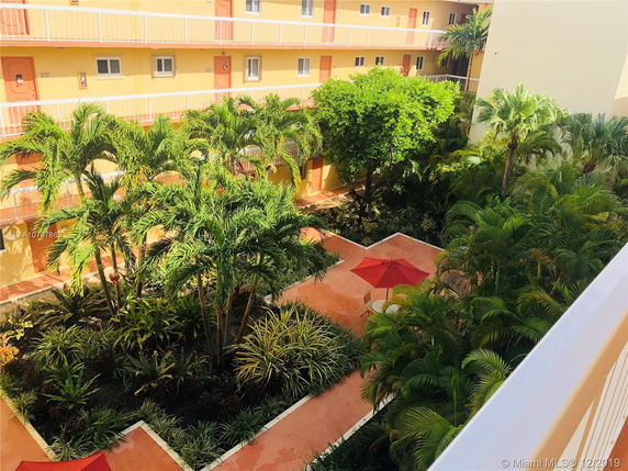 View of a building courtyard with lush greenery and red umbrellas.