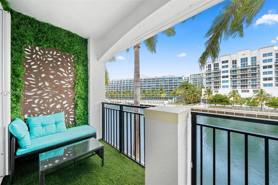 Balcony view of a waterfront residential area with modern apartment buildings and palm trees.