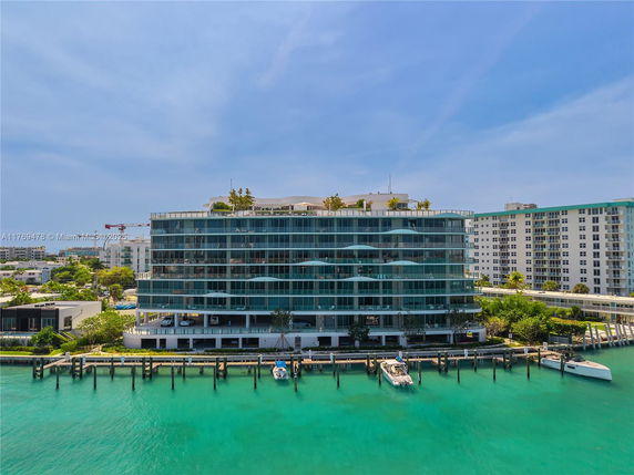 Front view of a multi-story waterfront building with large windows and balconies.