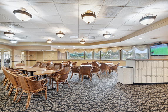 Recreational area with wicker chairs and tables in a well-lit room.