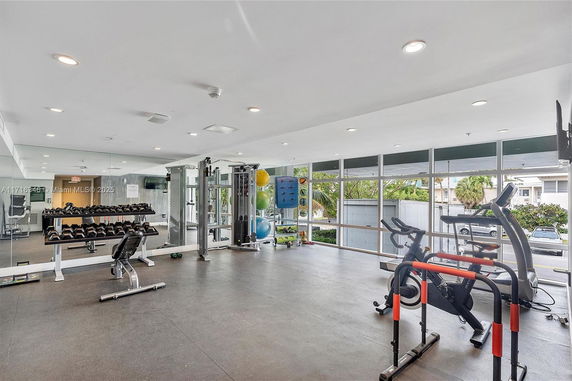 Interior view of a gym area with exercise equipment and large windows.