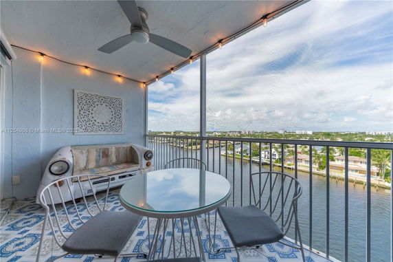 Balcony with a decorative bench and table, overlooking a waterway and distant buildings.