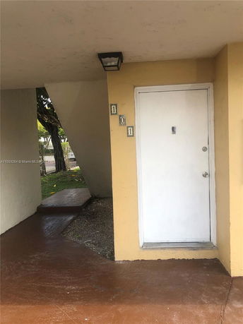 View of a building entrance with a closed white door and beige walls.