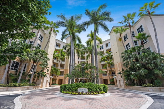 Front view of a multi-story building with palm trees in the courtyard.