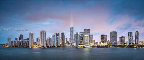 Panoramic view of a city skyline with numerous skyscrapers along a waterfront.