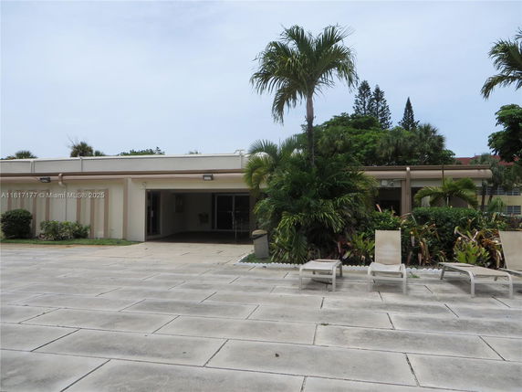 Front view of a single-story building with a covered entrance and surrounding palm trees.