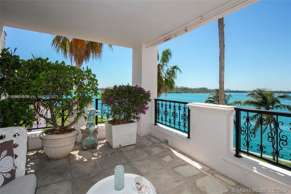 View from a terrace overlooking a body of water with decorative railings and potted plants.