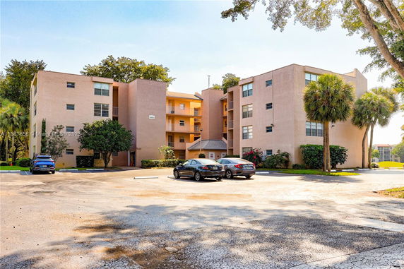 Front view of a multi-story residential building with a parking area in front.