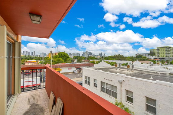 View from a building balcony overlooking a busy street and city skyline.