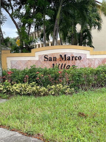 Sign for San Marco Villas surrounded by greenery and trees.