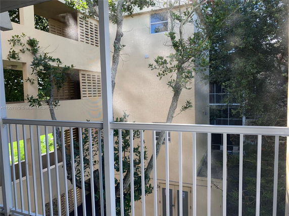 View from a balcony showing nearby building and trees.