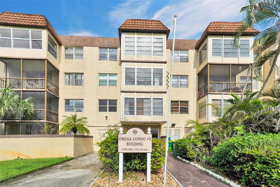 Front view of a multi-story condominium building with enclosed balconies.