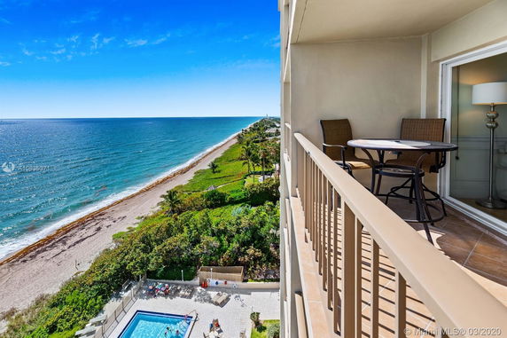 Balcony view overlooking the ocean and beach with a swimming pool below.