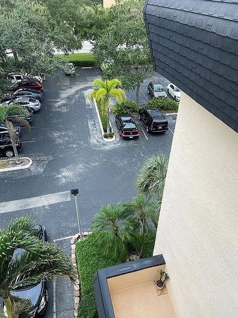 View of an outdoor parking area with several parked cars and surrounding trees.