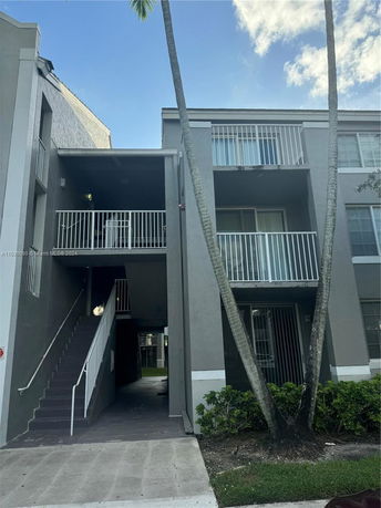 Front view of a multi-story apartment building with balconies and a staircase.