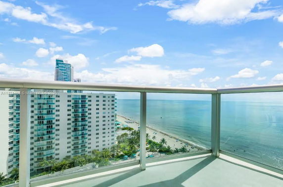 Panoramic view from a balcony overlooking buildings and the ocean.