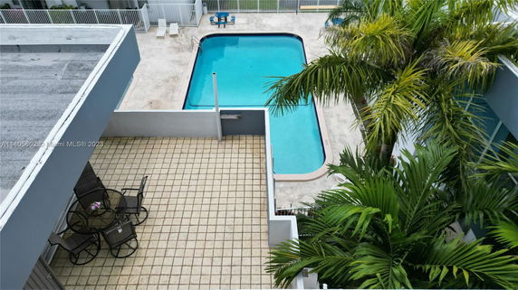 Top view of a swimming pool area with a patio and outdoor seating.