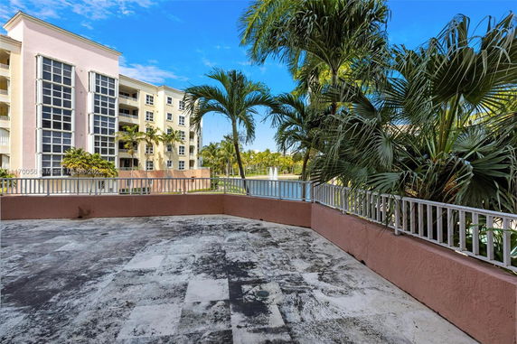 Rooftop view of a multi-story residential building with large windows and palm trees.