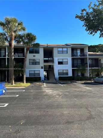 Front view of a two-story apartment building with balconies and a central stairway.
