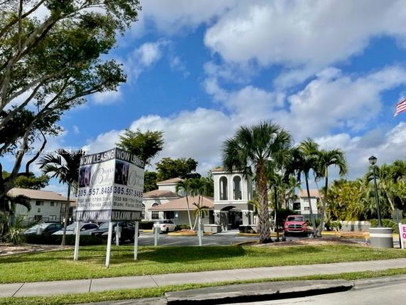 Front view of a multi-story building with leasing signs in front.