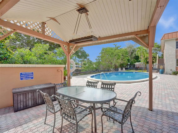 Outdoor swimming pool area with a pergola and seating.