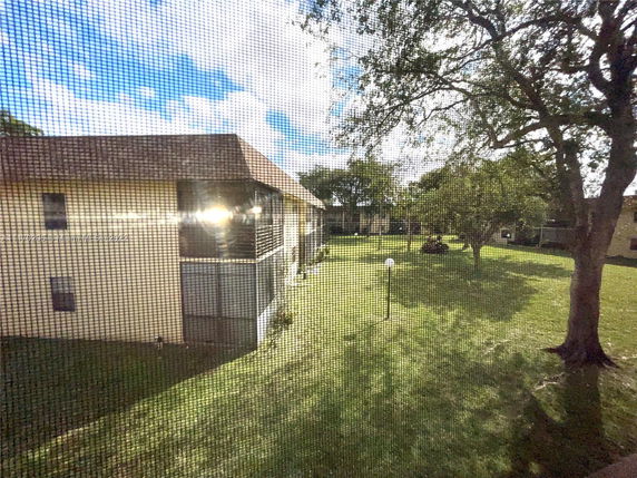 View of residential buildings and green lawn through a mesh screen.
