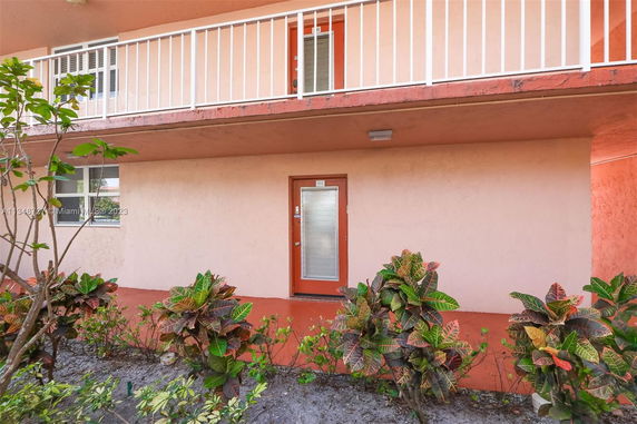 Front view of a two-story building with red door and balcony with railing.