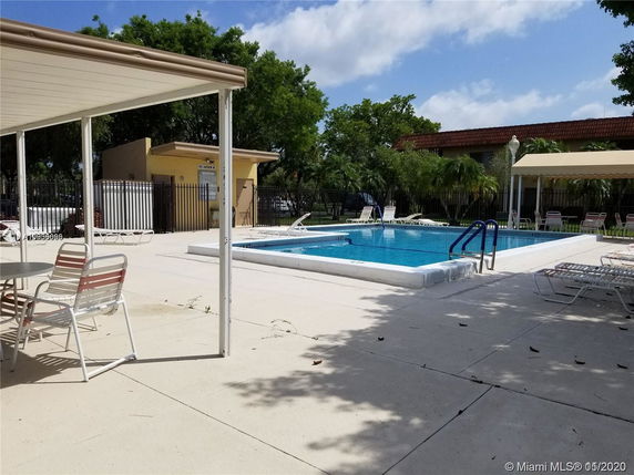 Outdoor area with a swimming pool, surrounded by lounge chairs and shaded seating areas.