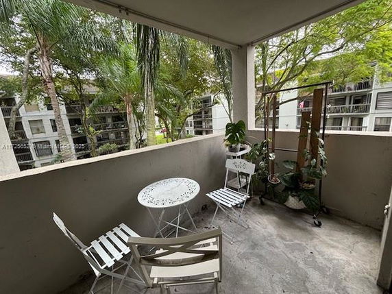 View from a balcony with outdoor seating and plants overlooking other buildings.