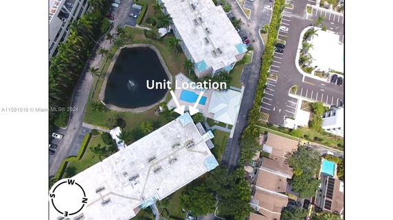Aerial view showing buildings, a swimming pool, and parking areas.