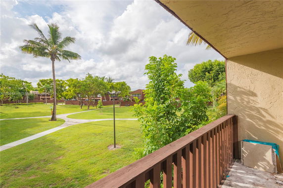 View from a balcony overlooking a grassy area with walkways and trees.