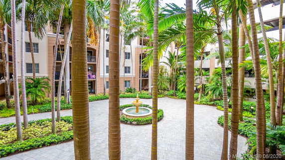 Courtyard view with palm trees and a central fountain surrounded by apartment buildings.