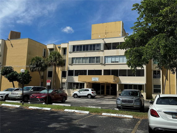 Front view of a multi-story building with parking area.