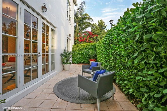 Side view of a house with large glass doors and lush greenery.