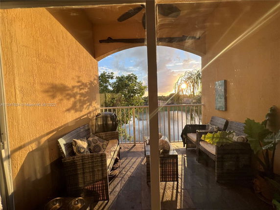 Balcony view with outdoor seating overlooking a lake and trees.