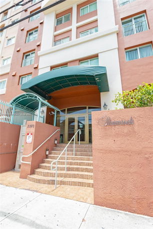 Front view of a multi-story building with an entrance canopy and steps leading up.
