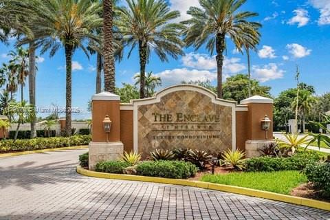 Entrance sign of The Enclave at the Fairways with palm trees in the background.