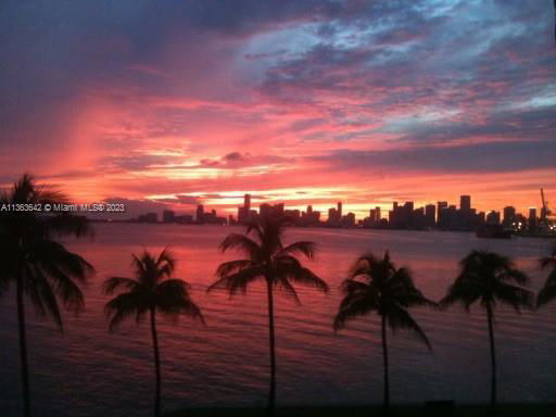 Silhouette of a city skyline at sunset with palm trees in the foreground.