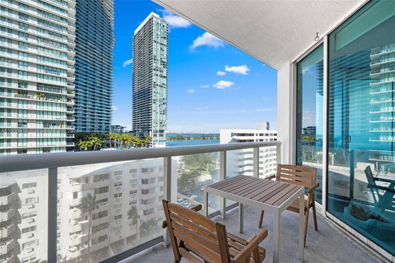 Balcony view of high-rise buildings and distant water body.