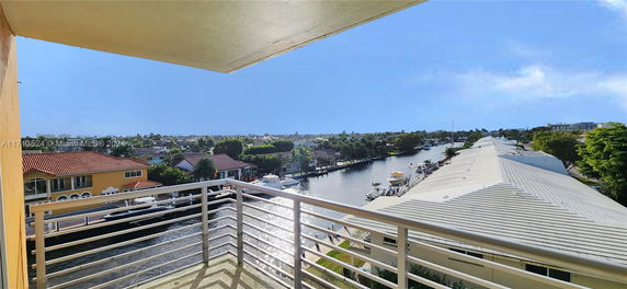View from a balcony overlooking a canal with houses and boats.